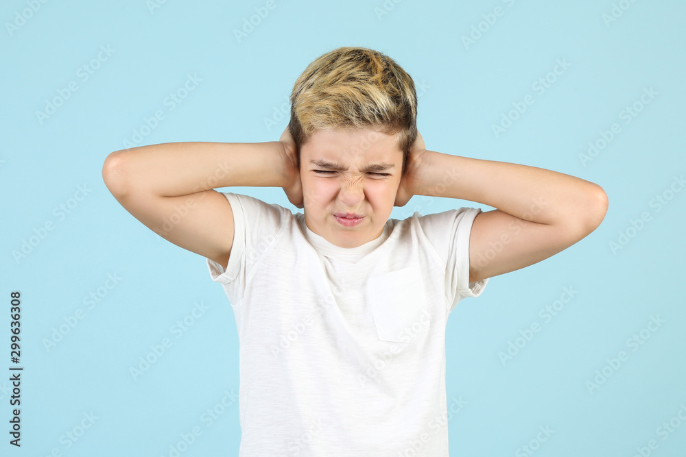 Young boy closing ears by hands on blue background Young boy closing ears by hands on blue background