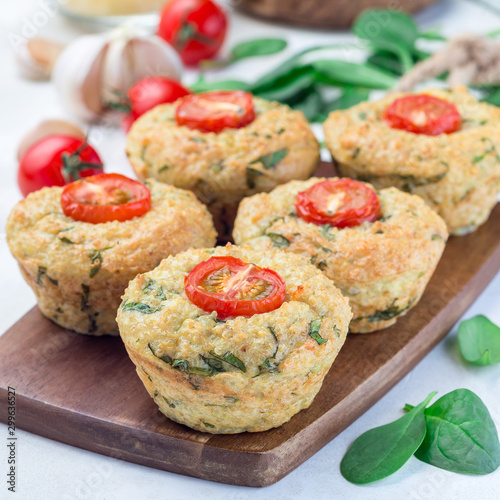 Savory muffins with quinoa, cheese and spinach topped with tomato, on wooden board, square format