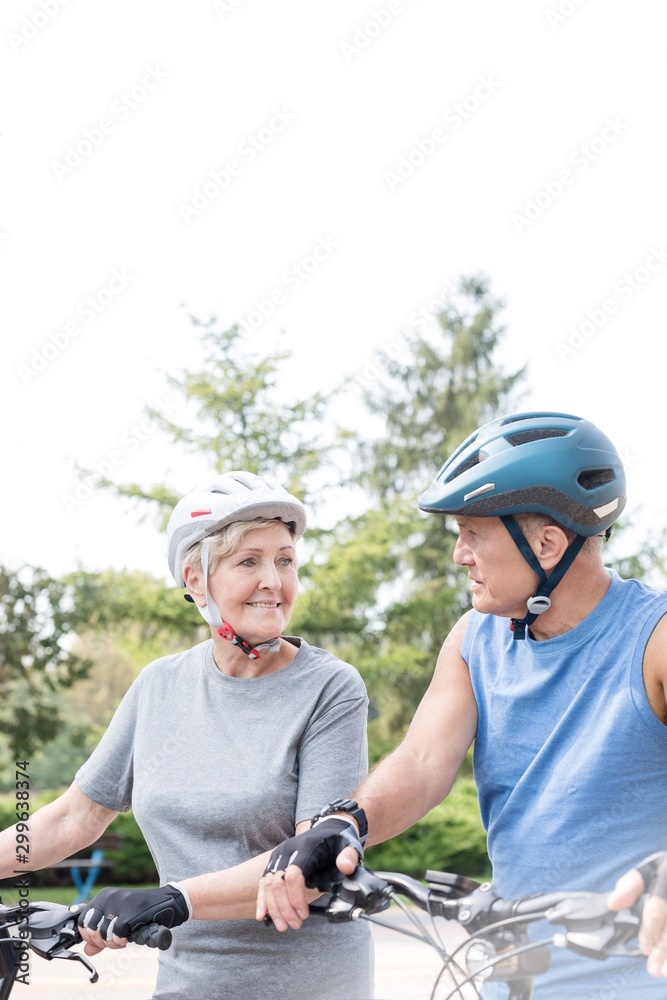 Fit senior couple with bicycles looking at each other