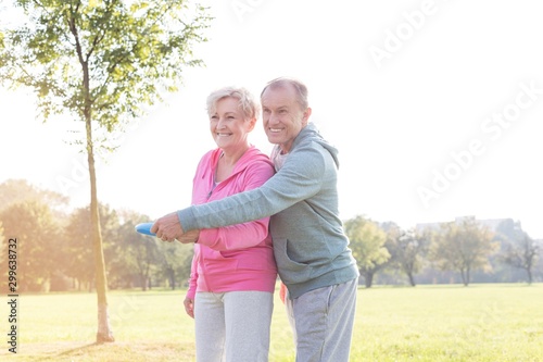 Loving active couple throwing flying disc together in park