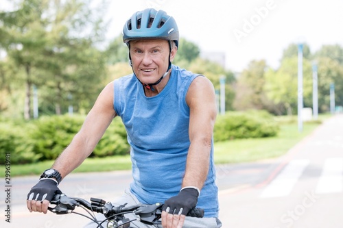 Portrait of senior man wearing helmet while riding bicycle in park