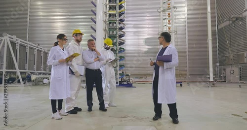 Scientists and engineers meeting at large modern electricity laboratory. Asian, black and caucasian colleagues duscuss results of new experiment photo