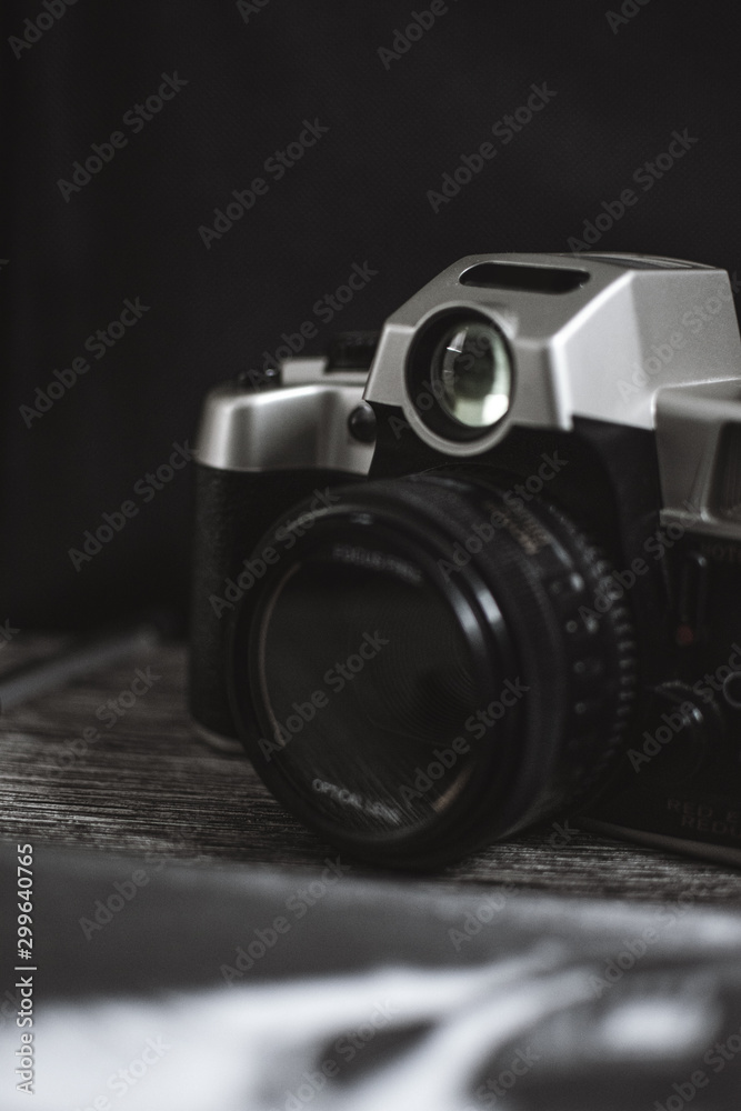 Silver and black analog camera over a wood texture and black background 