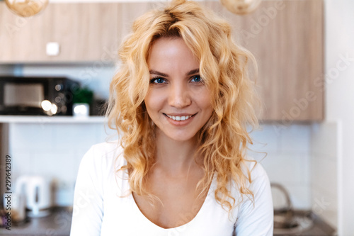 At home. Woman portrait. Blonde girl is looking at camera and smiling  in the kitchen