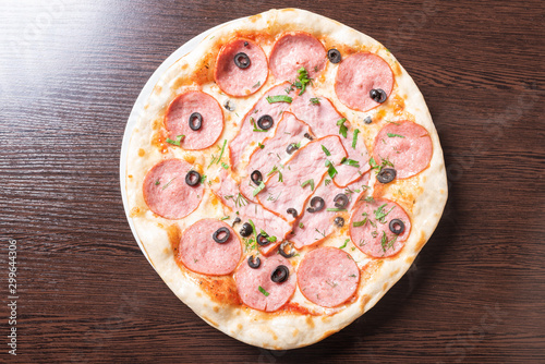 Cheap pizza with pepperoni, ham, olives and herbs.