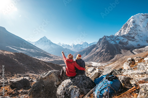 Couple having a rest on Everest Base Camp trekking route near Dughla 4620m. Backpackers left Backpacks and trekking poles and enjoying valley view with Ama Dablam 6812m peak  and Tobuche 6495m photo