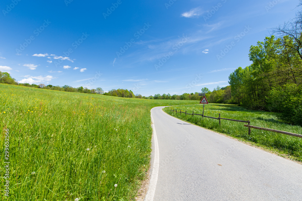 Strada asfaltata tra campi erbosi in una giornata di sole Strada asfaltata tra campi erbosi in una giornata di sole