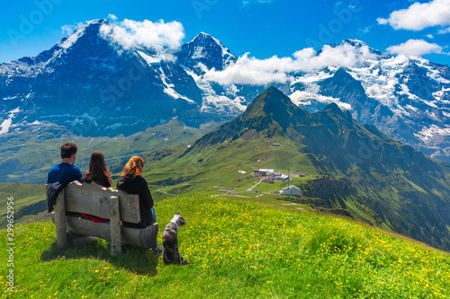Tourists admire Eiger, Monch and Jungfrau mountains from summit of mountain Mannlichen, popular viewpoint in Swiss Alps, Switzerland.