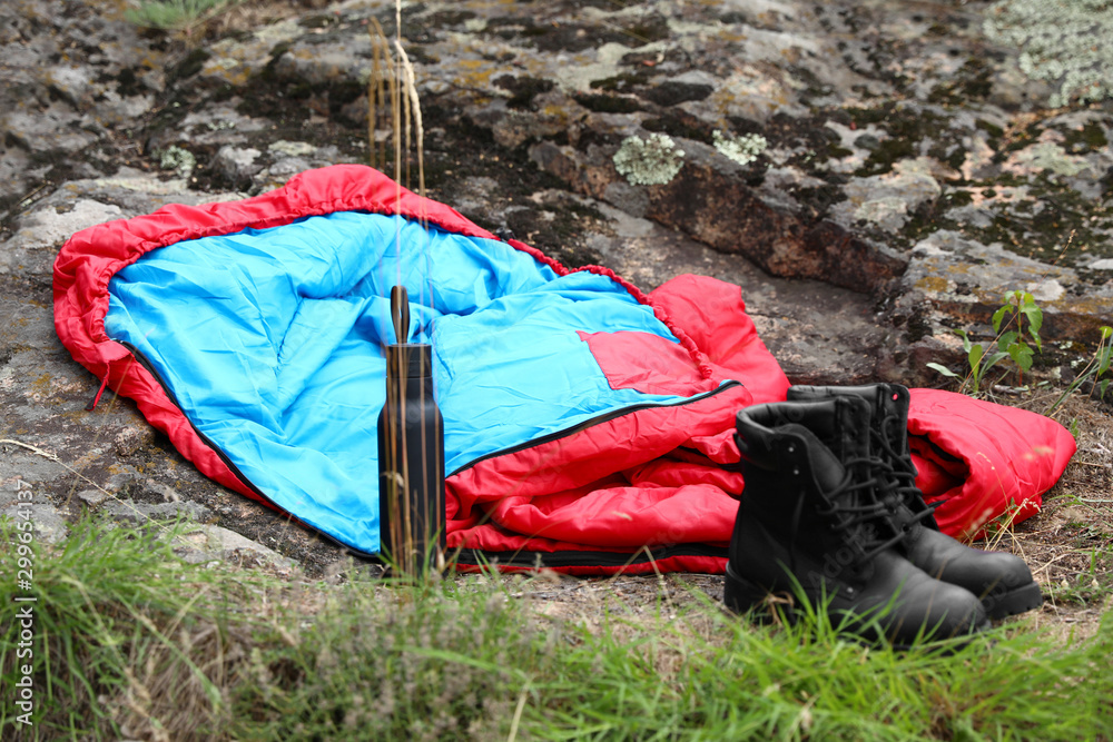 Sleeping bag, boots and bottle outdoors. Camping gear Stock Photo | Adobe  Stock