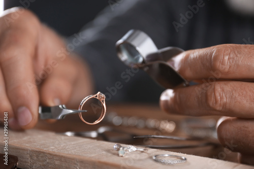 Male jeweler examining diamond ring in workshop, closeup view