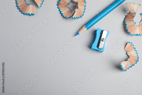 Color pencil, sharpener and shavings on grey background, flat lay. Space for text