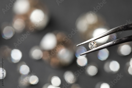Tweezers with beautiful gemstone on blurred background. Space for text