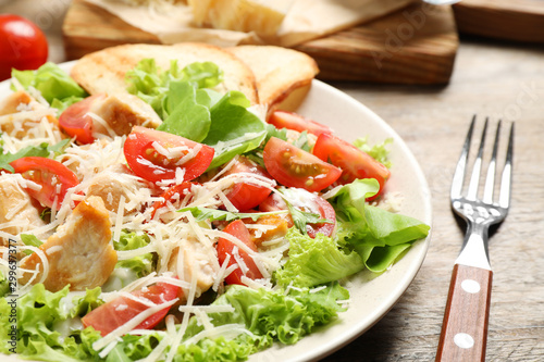 Delicious fresh Caesar salad on wooden table, closeup