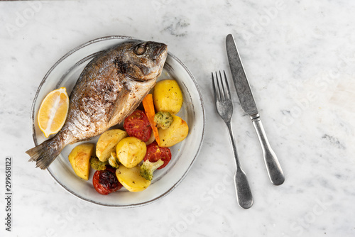 Baked dorado (dorada) fish on a plate, top view