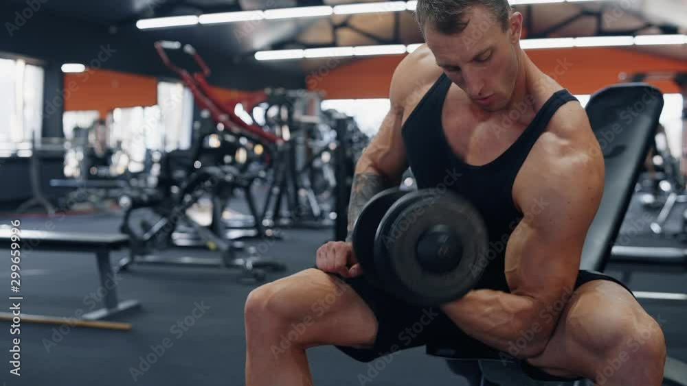 Sporty young man doing exercise with dumbbells. Strong chest and shoulder muscles. Bodybuilding concept Sporty young man doing exercise with dumbbells. Strong chest and shoulder muscles. Bodybuilding concept