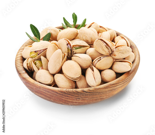 Bowl with tasty pistachio nuts on white background