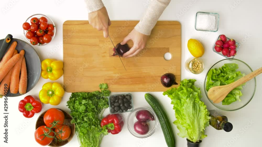 healthy eating, vegetarian food and cooking concept - young woman with kitchen knife chopping red onion on wooden cutting board at home