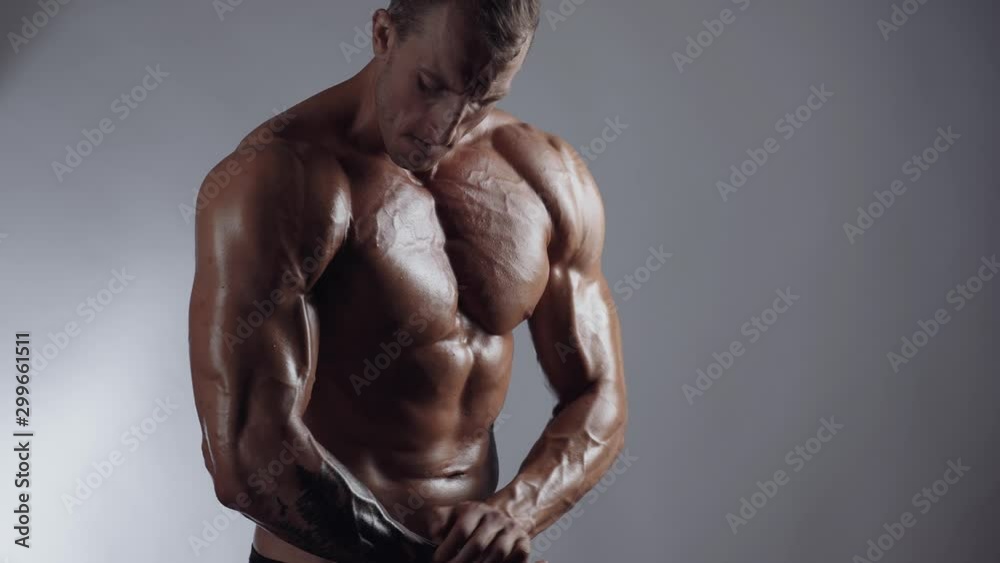 Handsome shirtless athletic man posing on a gray background. Athletic bodybuilder posing Handsome shirtless athletic man posing on a gray background. Athletic bodybuilder posing