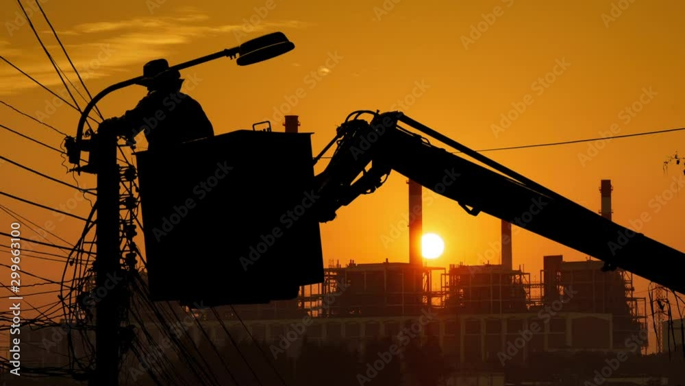 Silhouette of an electrician to repair street lighting with sunset time lapse