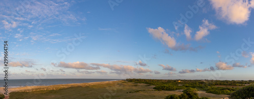 Seaside with sand dunes and colorful sky at sunset.