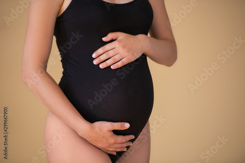 Pregnant tummy close up. Pregnant girl in an elegant black bodysuit. Beautiful healthy pregnancy. Minimalism.