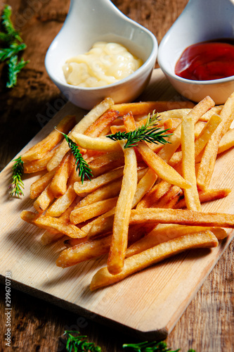 Crispy fry fries placed on a wooden chopping board with two dipping sauces, mayonnaise, tomato sauce