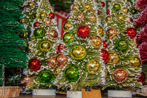 Background of miniature flocked Christmas trees with shining round ornaments - selective focus on foreground