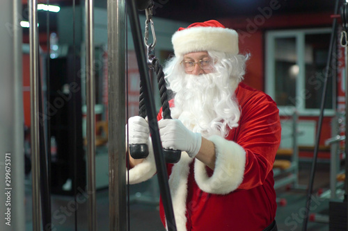 Santa Claus training at the gym on Christmas Day. Santa Claus working doing exercises at triceps.