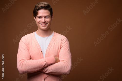 Studio shot of young handsome man against brown background