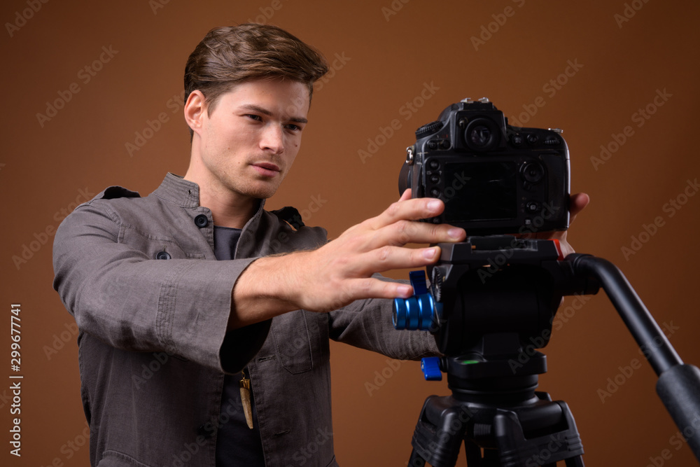 Studio shot of young handsome man vlogging with camera Studio shot of young handsome man vlogging with camera
