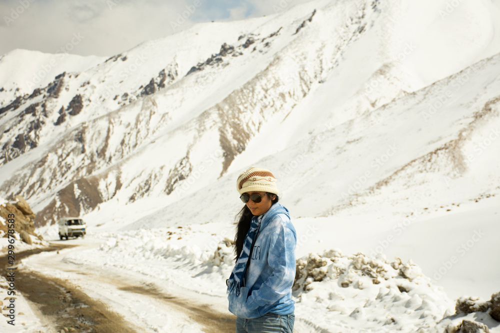 Travelers thai woman travel visit stand for take photo at Khardung La Road on top of himalaya mountain between go to Nubra valley village at Leh Ladakh while winter season in Jammu and Kashmir, India
