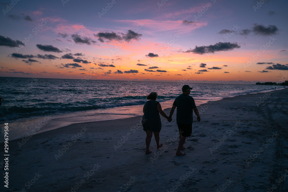 A couple walking under sunset beautiful sky at Anna Maria Beach Beadeton Florida