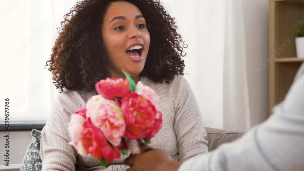 valentines day, greeting and love concept - happy african american couple with bunch of flowers at home valentines day, greeting and love concept - happy african american couple with bunch of flowers at home
