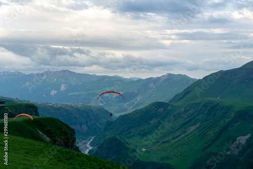 Gudauri, Kazbegi, Georgia: people paragliding through the Devils Valley in the Caucasus mountains. In the background the colorful peak