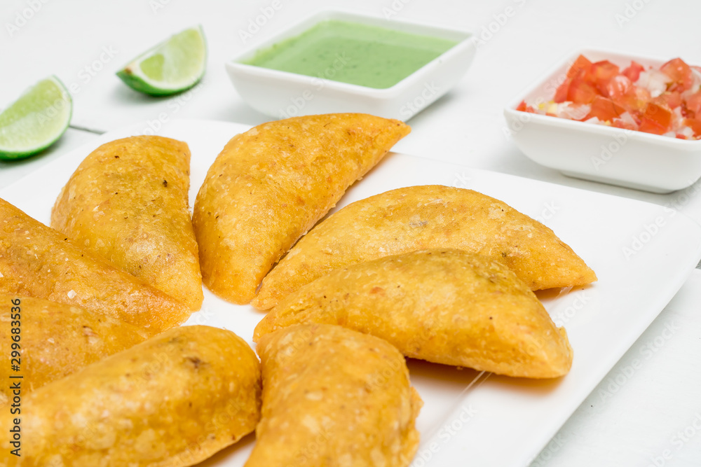 Colombian empanadas, chili and lemon on white wooden boards