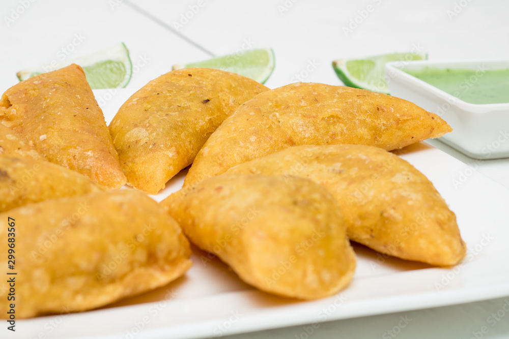 Colombian empanadas, chili and lemon on white wooden boards Colombian empanadas, chili and lemon on white wooden boards