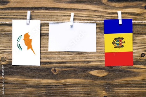 Hanging flags of Cyprus and Moldova attached to rope with clothes pins with copy space on white note paper on wooden background.Diplomatic relations between countries.