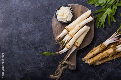 Fotografiet Fresh orgaanic horseradish or Horse-radish root on wooden cutting board