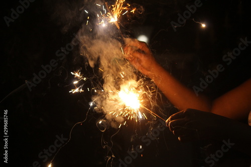 human Hand holding the sparkler on sparkling with dark background with some white smoke on the deepavali / dewali celebration © balamurugan