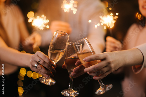 Close-up of glasses of clinking Champagne with Bengali lights. Celebration concept