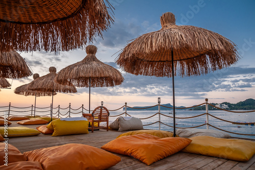 Straw umbrellas and pillows on the seashore pier.