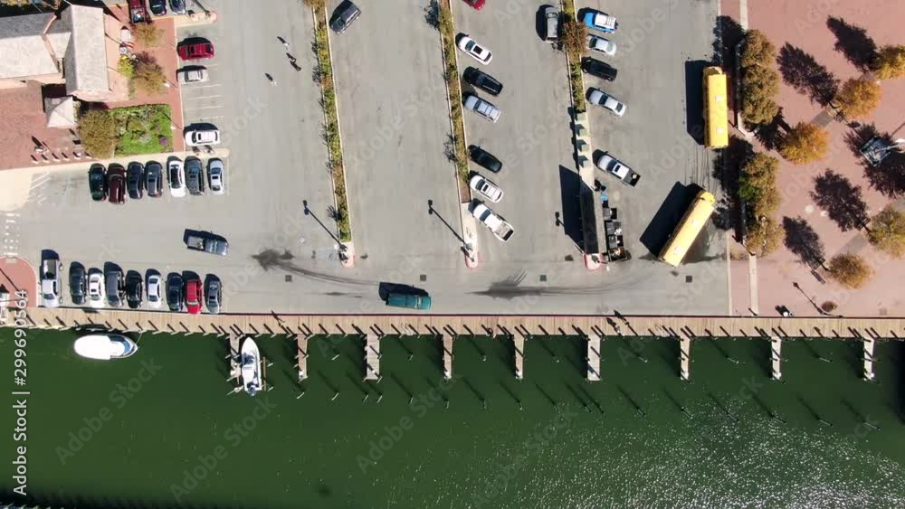 Top down aerial of empty boat docks in harbor, green water, parking lot, school bus Top down aerial of empty boat docks in harbor, green water, parking lot, school bus