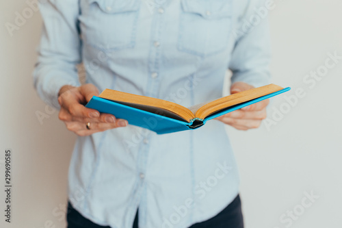 Beautiful female hands hold an open book or magazine in the room