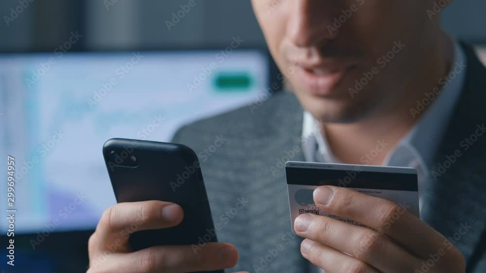 Close up portrait business man shopping online with credit card using smartphone at office. Online banking mobile app.