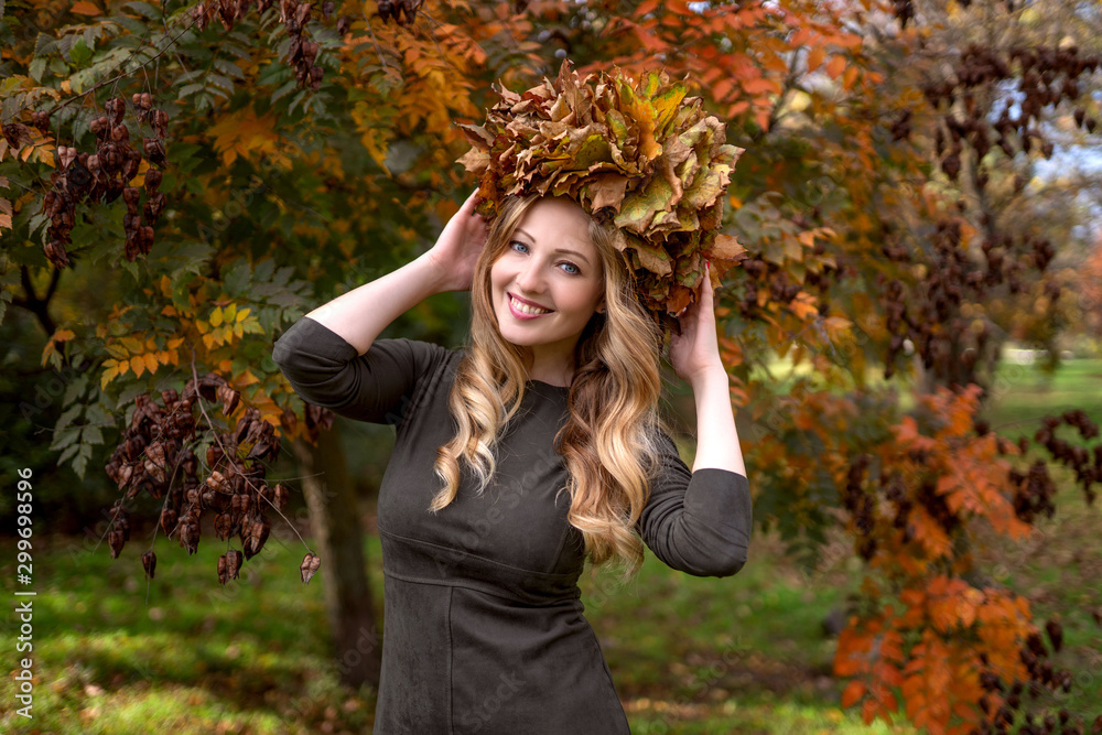 Beautiful woman over 35 years old in autumn park with a crown of leaves on her head, smiling Beautiful woman over 35 years old in autumn park with a crown of leaves on her head, smiling