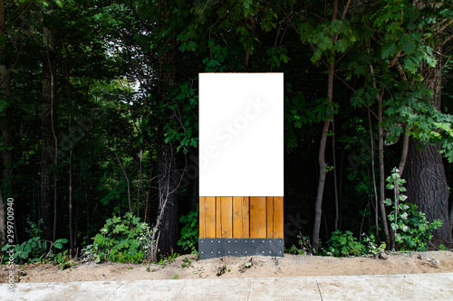 Blank vertical billboard on green grass in park to place your logo or advertising on it on wooden stand
