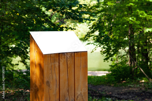Blank horizontal information sign on wooden stand on green grass in park
