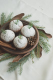 Christmas wreath imitation with a plate of cupcakes. Dessert decorated with fir branches and cones on a white background.