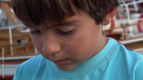 Ucagiz, Turkey - 29st of September 2019: 4K Face of a child gnawing his nails, a boat in the background photo