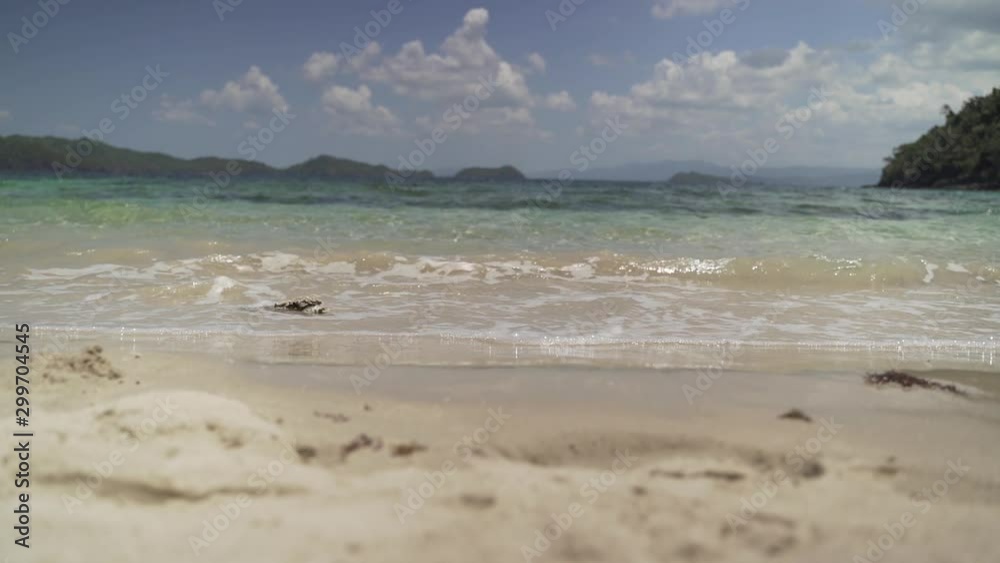 Low shot of sea calmly waving onto tropical sandy beach - close Low shot of sea calmly waving onto tropical sandy beach - close